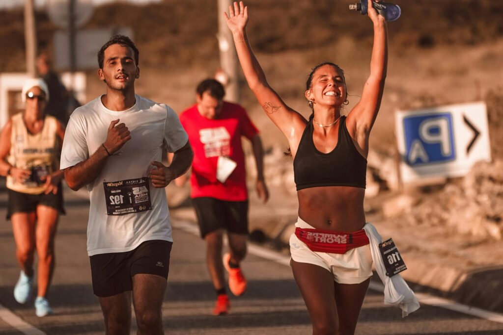 Marathon participants celebrating victory with joyful expressions on a sunny day.